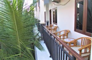 uma varanda com cadeiras e uma palmeira em Anantaya Home em Denpasar
