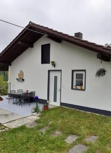 a white house with a patio and a table at Ferienhaus Bayerwald in Ringelai