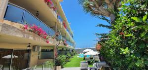 ein Gebäude mit Stühlen, Sonnenschirmen und Pflanzen in der Unterkunft Alsol Don Palomón in Playa del Ingles