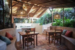 un patio con mesa, sillas y sofá en Tofinho Beach House Apartments en Inhambane