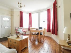 a living room with red curtains and a table and chairs at The Nook in Tywyn