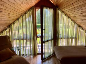 a bedroom with large windows and a couch in a room at Brīvdienu mājas Pārupes in Bauska