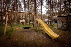 a playground with two swings and a slide at Villa Marika Holiday Centre in Alajõe