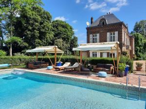 - une piscine avec des chaises et des parasols en face d'une maison dans l'établissement Manoir des Tuileries du Buisson, à Verneuil-sur-Avre