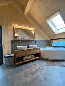 uma casa de banho com 2 lavatórios, uma banheira e um espelho. em Bergchalet Stolzalpe 