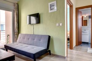 Achilleas Apartments في كاليفيا بوليغيرو: غرفة معيشة مع أريكة وتلفزيون على الحائط