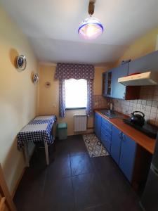 eine Küche mit blauen Schränken, einem Tisch und einem Fenster in der Unterkunft Majkowiczówka in Czorsztyn
