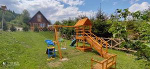 a playground in a yard with a house at Domki Bieszczadzki Czar Rodzinny 661-850-410 in Polańczyk