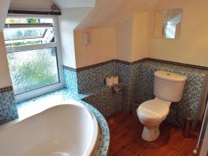 a bathroom with a tub and a toilet at Poet's Cottage in Trefriw