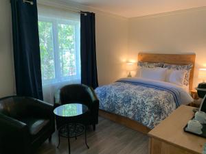 a bedroom with a bed and a chair and a table at Auberge la Rosepierre bistro Henri in Grandes-Bergeronnes