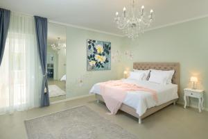 een witte slaapkamer met een bed en een kroonluchter bij Holiday Home Plasa in Žrnovnica +45 foto's