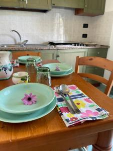 un tavolo in legno con piatti e utensili. di Villa Anna Sorgeto a Ischia