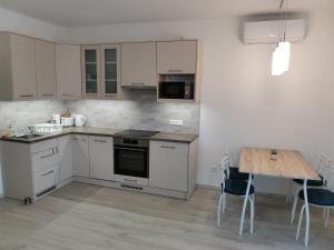 a kitchen with white cabinets and a wooden table at Éva Apartmanház in Csopak