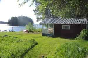 a small cabin in the grass next to a lake at Stugor Storsjöns strand in Hackås