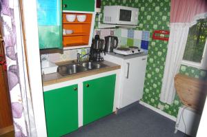 uma pequena cozinha com armários verdes e brancos e um lavatório em Stugor Storsjöns strand em Hackås