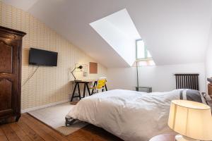 a bedroom with a bed and a tv on the wall at La maison des couturières in Cluny