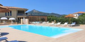 - une piscine avec des chaises et une maison dans l'établissement Résidence Storia d'Estate, à LʼÎle-Rousse