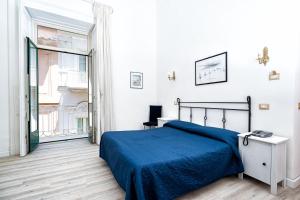 a white bedroom with a blue bed and a window at Hotel Fontana in Amalfi