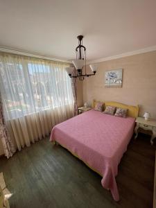 a bedroom with a pink bed and a window at Provence Deluxe Apartment in Atia Resort in Chernomorets