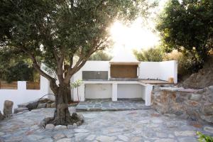 un albero davanti a un muro bianco con stufa di Villa Aloni in Triopetra a Triopetra