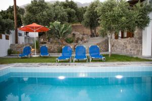 grupa niebieskich krzeseł i parasol obok basenu w obiekcie Villa Aloni in Triopetra w mieście Triopetra