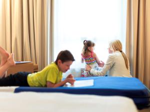 a boy and two girls sitting on a bed and a boy at Novotel Mohammedia in Mohammedia
