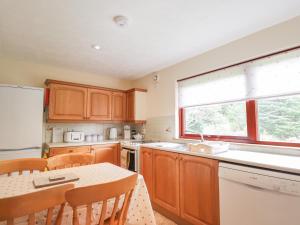 a kitchen with wooden cabinets and a table and a window at Rowan Bank in Spean Bridge