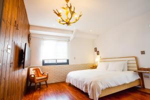 a bedroom with a bed and a chair and a chandelier at 4 Design Inn in Tainan