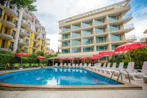 basen z leżakami i parasolami przed budynkiem w obiekcie Deva Hotel - All Inclusive w Słonecznym Brzegu