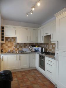 a kitchen with white cabinets and a stove top oven at Rowland House - Central Skipton, Dales Gateway in Skipton