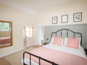 a bedroom with a large bed with pink pillows at Sea Pink Cottage in Swanage