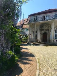 a large white house with a brick driveway at Hotel Garden in Bolesławiec