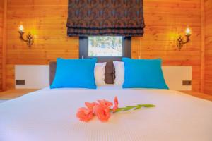 Una cama con almohadas azules y flores rosas. en Huzur Bungalows en İnlice