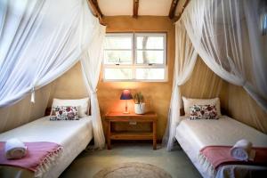 two beds in a room with a window at Tofinho Beach House Apartments in Inhambane