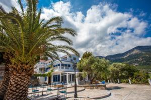 a palm tree in front of a building at Kinira Beach Hotel in Koinyra