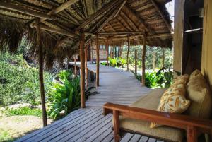 a wooden porch with a bench on a house at Tofinho Beach House Apartments in Inhambane