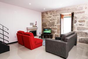 sala de estar con 2 sillas rojas y chimenea en Casa De Carcavelos, en Cabeceiras de Basto