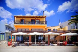 a building with tables and chairs and umbrellas at Scorpios Family Rooms in Palaiochóra