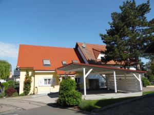 ein Haus mit einem orangenen Dach und einer Garage in der Unterkunft Ferienwohnungen Hog in Ringsheim