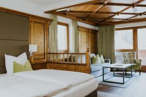 a bedroom with a bed and a couch and a table at Hotel Tauernhof in Grossarl