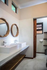 a bathroom with two sinks and mirrors on the wall at Tofinho Beach House Apartments in Inhambane