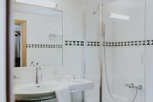 a white bathroom with a sink and a shower at Hotel Tauernhof in Grossarl