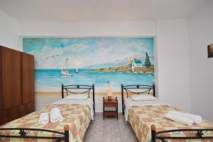 two beds in a room with a painting on the wall at KIPRIANOS - STUDIOS in Loutra Edipsou