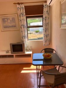 uma sala de estar com uma mesa e uma televisão em Apartamentos Mar-Sol Villas em Vilamoura