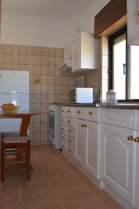 una cocina con armarios blancos y una mesa. en Apartamentos Mar-Sol Villas en Vilamoura