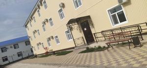 a building with two benches in front of it at Sulo Aksai Hotel in Aksay