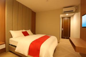 a bedroom with a bed with a red and white blanket at Adotel in Jakarta