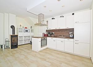a white kitchen with white cabinets and a fireplace at Heimathafen An Seen & Meer in Korswandt