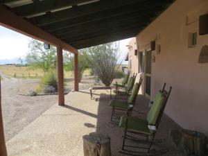 a row of green chairs sitting on a porch at Rancho Milagro Bed & Breakfast in Elgin
