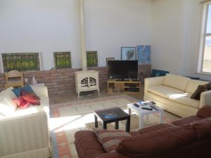 a living room with couches and a flat screen tv at Rancho Milagro Bed & Breakfast in Elgin